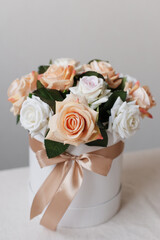 Artificial roses in a round box on a white table. Decorative bouquet of flowers.