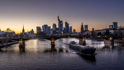 Fototapeta na wymiar The skyline of Frankfurt at sunset, seen from a bridge at the river Main at a cold day in winter.