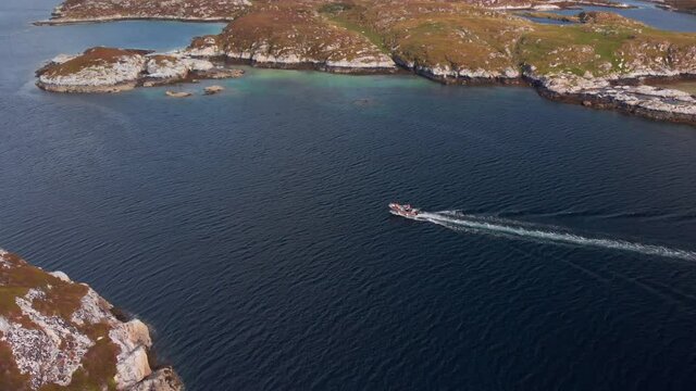 Fisher boat on the norwegian coast. Small ship cruising through beautiful islands in shallow water. Aerial drone video at Froya, Norway.
