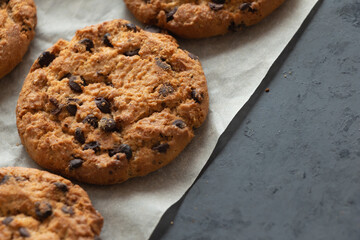 Crispy oatmeal cookies with chocolate on baking paper. Homemade cakes.