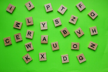 English alphabet. The letters are arranged chaotically on a green background. View from above. Words. Toy bricks on a green background. English language. Grammar.