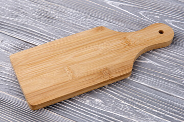 Wooden kitchen cutting board. The item is on the gray texture table. Cooking accessories.