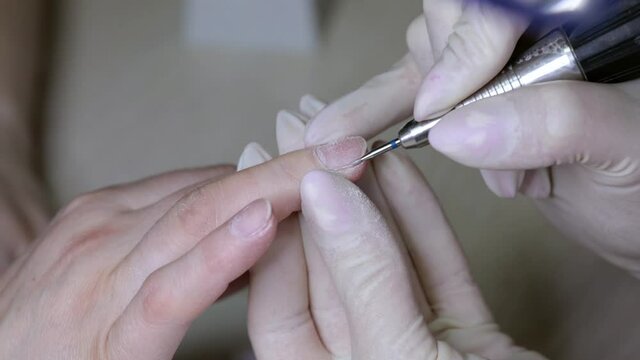 Processing rough cuticles and lateral nail folds on the hands with a small instrument. Medical hardware manicure in a beauty salon.