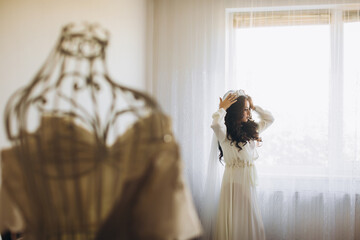 Bride's fees. The bride plays with a veil. Bride with elegant hairstyle with crown and makeup. Wedding. Beautiful happy bride preparing for her wedding. Happiest bridal day. Bride with fashion dress