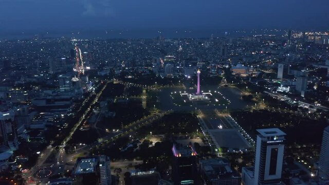 Wide aerial dolly view of Indonesian national monument Monas symbolizing independence in large pubic park in Jakarta 