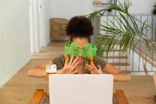 Happy mixed race woman celebrating st patrick's day making video call and waving