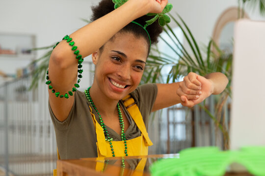 Happy mixed race woman celebrating st patrick's day making video call and dancing