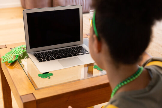 Mixed race woman celebrating st patrick's day making video call using laptop