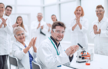 group of young scientists congratulating their colleague with applause