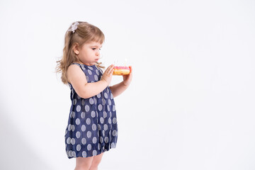 cute happy little girl in blu dress blow out the candle on a birthday cake on white background