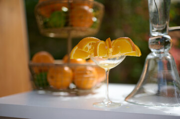 Glass with orange slices standing on the table. vase with oranges on the background