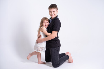 Fototapeta na wymiar handsome older brother teenager hugging his cute little sister on white background