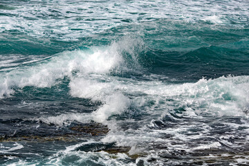 Crystal clear sea water of Mediterranean sea. Sea waves break on the shore after a storm. 
