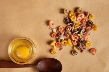 pasta, wooden spoon and raw egg on the table. Italian pasta on paper.  ingredients 