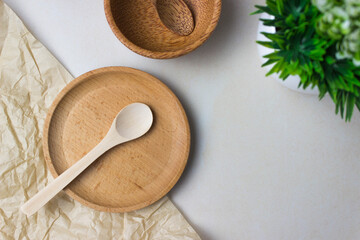 Wooden utensils on the kitchen table. Round wooden plates, a spoons, a green plant. The concept of serving, cooking, interior details. Top view