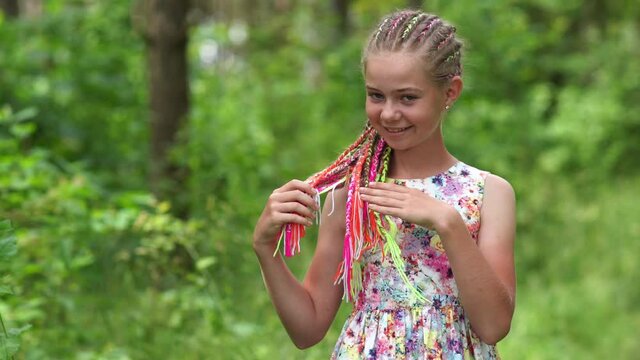 Teenage girl with multi-colored dreadlocks in the forest.