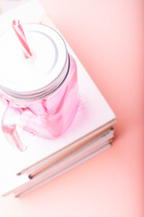Literature concept. White books with a pink cup on a pink background.