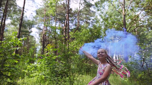 A teenage girl with blue smoke walks in the forest.