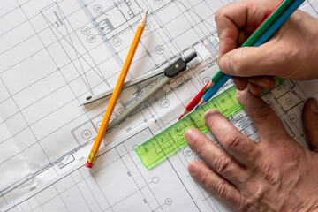 The planner makes a drawing of the building with coloured pencils. The porous texture of the drawing paper. Graphite pencil, circular, ruler lie on the drawing