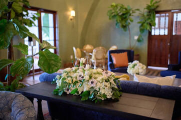 Arrangement of white flowers and greens on the table in the room