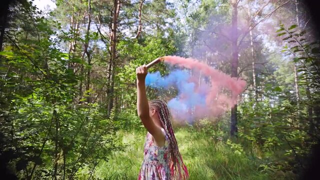 A teenager girl with colored smoke walks in the forest.