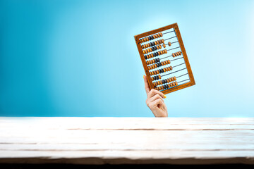 Girl holding old wooden scratched vintage decimal abacus on a blue blank background. Space for...