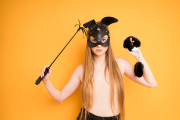 Dominant Woman in a fetish mask holds a leather whip in her hand and handcuffs for adult games. Sex...