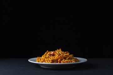 Italian pasta on a dark background. Italian pasta in tomato sauce on a black background. Home traditional cuisine.