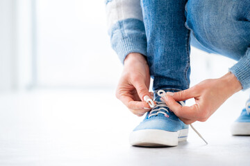 Person tying laces on gumshoes at home
