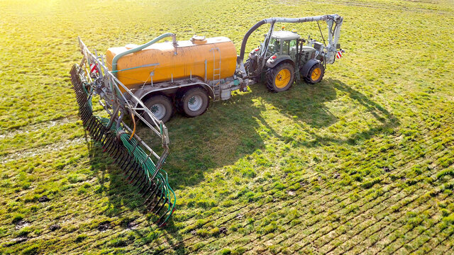 Traktor mit G&uuml;lletonne bringt G&uuml;lle auf Wiese aus, Industrielle Landwirtschaft aus der Vogelperspektive