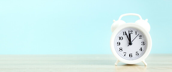 Close-Up Of Alarm Clock On Table Against Blue Wall, banner format.