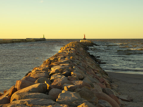 Two breakwaters at sunset. Two lighthouses mark the port gate.