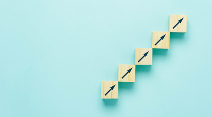 Top view arrow go up on wood block stacking same as step stair on  blue paper background, Business growth up concept. copy space for text. Abstract Success stock market . management achievement.