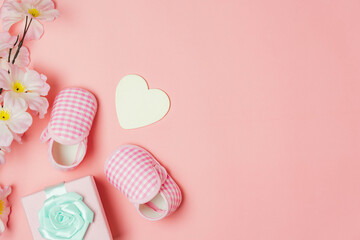 Top view aerial image of decoration Happy mothers day holiday background concept. Flat lay baby shoes and heart shape on modern beautiful pink paper at home office desk. pastel tone creative design.