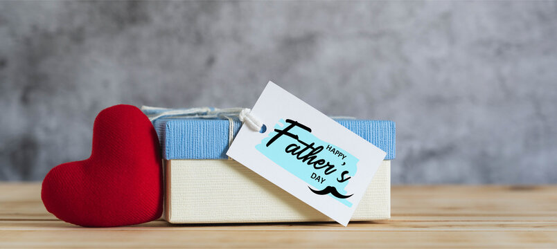 Objects on the table Happy Fathers day holiday background concept. Gift box with greeting card for love dad with accessories  sign of season the red heart Mustache. Blurred grey backdrop.