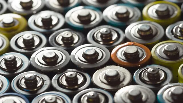 Preparing Batteries for Disposal. Dense AA battery array moves with slight rotation close-up with backlight