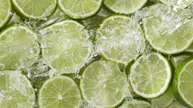 Super slow motion of lime slices with splashing water, top view. Filmed on high speed cinema camera, 1000 fps.