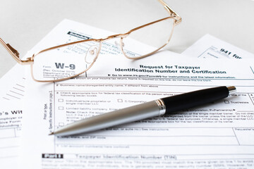 Federal income tax laws W9 form. Pen and spectacles