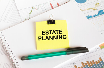 A yellow sticker with text Estate Planning is in a Notepad with a green pen financial charts and documents