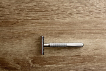 Reusable metal safety razor on wooden background. Top view.