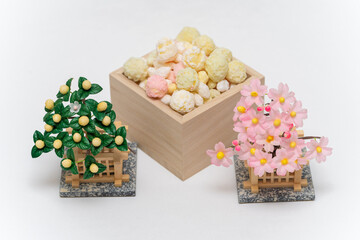 木製の桝(ます)に入ったカラフルな雛あられと梅の花
