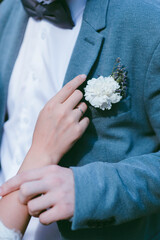 white butaniere on a blue jacket. Wedding ring. groom