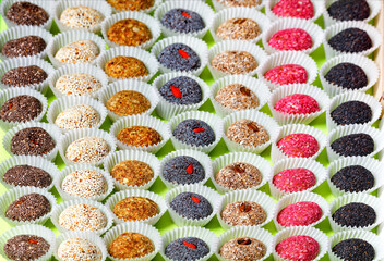 Handmade energy balls filled with various seeds in paper baskets in even rows.