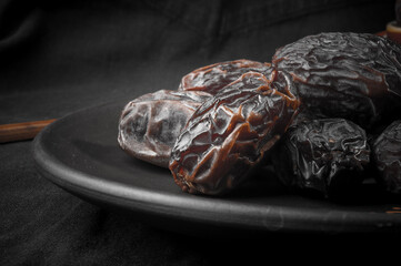 Big luxury dried date fruit in bowls on the dark surface, kurma ramadan kareem concept, close up.
