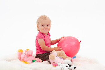 Fototapeta na wymiar A small baby girl in pink clothes plays on the floor with toys