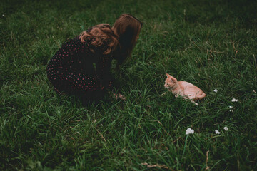The girl strokes a street cat in the summer. Homeless cat on the street.