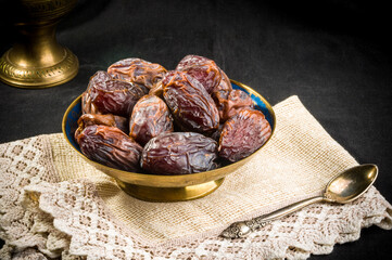 Big luxury dried date fruit in bowls on a linen napkin, kurma ramadan kareem concept, close up.