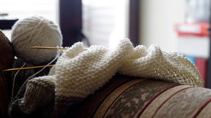 Fototapeta na wymiar Woolen yarn for knitting. Close-up shots of white ball of natural wool yarn and knitting needles