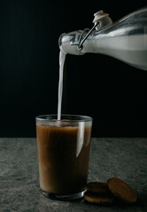 pour milk into coffee on a dark background
