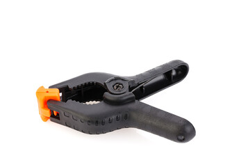 Plastic spring clamp isolated on white background. Clamping equipment. Working hand tool. Black and orange spring clamp. Close-up.